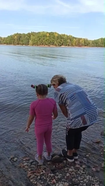 Pembe SensoryRuns giysisiyle göl kenarında bir yetişkinle yürüyen çocuk