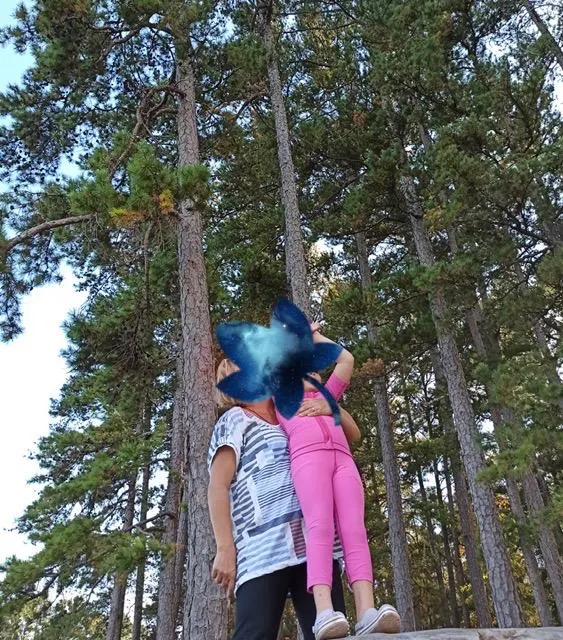 Pembe SensoryRuns giysisiyle ormanda yetişkin eşliğinde duran çocuk